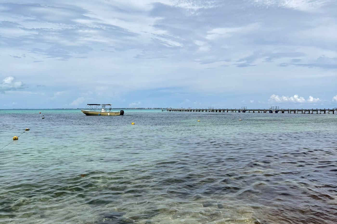 Shallow clear water, a small boat and a pier