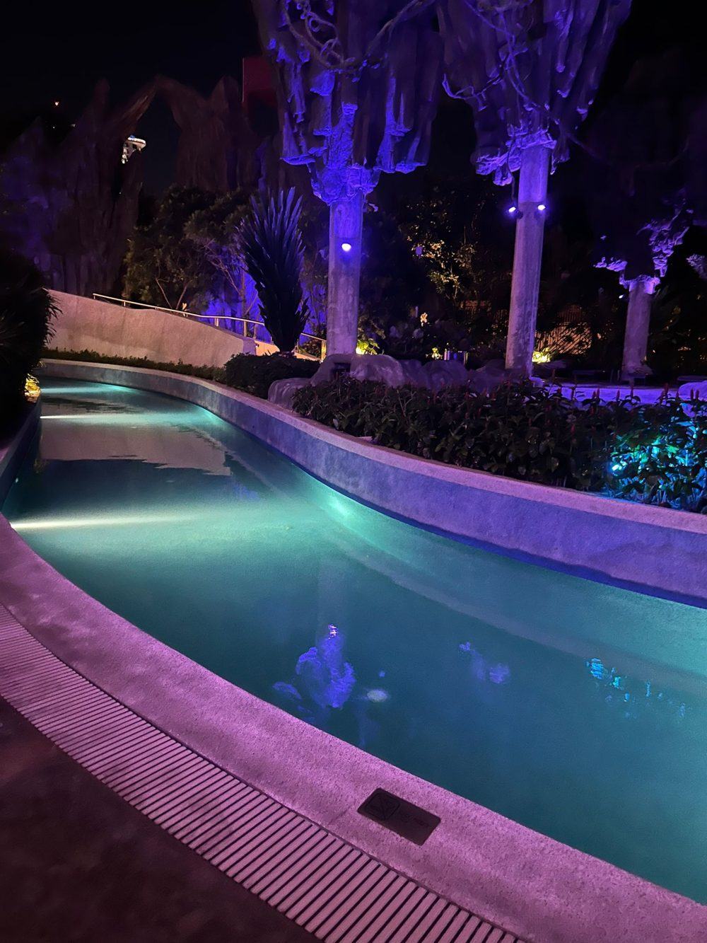 Curved lazy river lit in purple and green at night