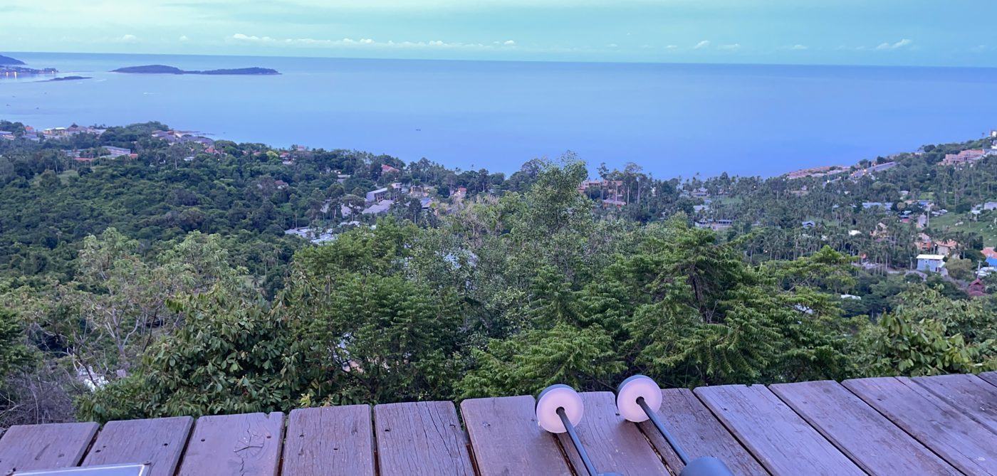 View from a hillside wooden deck over trees, the Samui coast and the sea